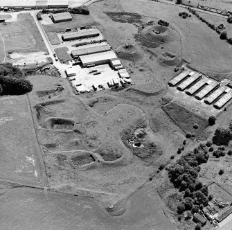 Oblique aerial view centred on Unit 2 of the explosves works and armament depot, showing the earthworks for burette houses and charge houses and a type 24 pillbox taken from the N.  
Also visible is Edingham Industrial estate with Edingham farm poultry houses.
