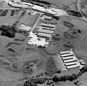 Oblique aerial view centred on Unit 2 of the explosves works and armament depot, showing the earthworks for burette houses and charge houses taken from the NW.  In the background is the S canteen and loading banks
Also visible is Edingham Industrial estate with Edingham farm poultry houses.