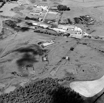 Oblique aerial view centred on the S part of the explosives works and armament depot showing the magazine area with earthworks for internal tranway system from the E.  In the background is part of  Unit 2 with the S canteen and railway loading bank.