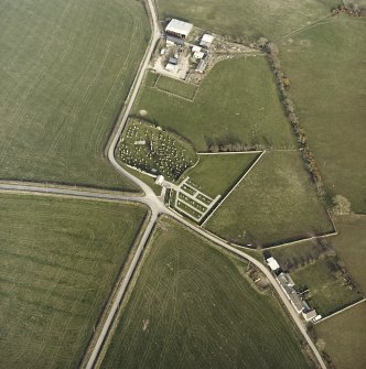 Oblique aerial view centred on the remains of the church and burial-ground with buildings and enclosures adjacent, taken from the W.