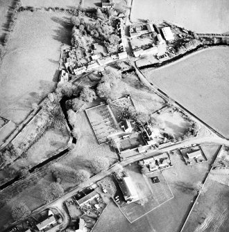 Oblique aerial view of Kirkgunzeon centred on the church, churchyard, manse and road bridge, taken from the W.