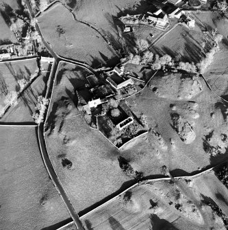 Oblique aerial view centred on the church, burial ground, manse and farmstead with smithy adjacent, taken from the SW.