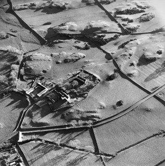 Oblique aerial view centred on the church, burial ground, manse and farmstead with smithy adjacent, taken from the NW.