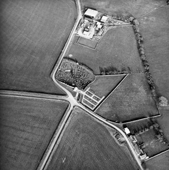 Oblique aerial view centred on the remains of the church and burial-ground with buildings and enclosures adjacent, taken from the W.