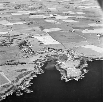 Oblique aerial view, taken from the SSE, centred on the village and harbour, Isle Head fort and the remains of St. Ninian's Chapel.