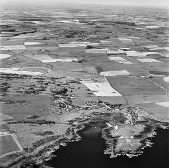Oblique aerial view, taken from the SSE, showing the village and harbour, Isle Head fort and the remains of St. Ninian's Chapel in the bottom right-hand corner of the photograph.