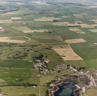 Oblique aerial view, taken from the SE, showing the village and harbour in the bottom right-hand corner of the photograph.