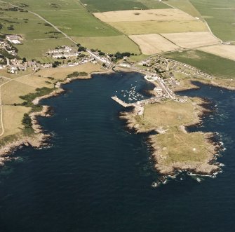 General oblique aerial view centred on the village, harbour, and the remains of the chapel and promontory fort, taken from the SSE.