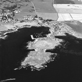 General oblique aerial view centred on the village, harbour, and the remains of the chapel and promontory fort, taken from the SE.