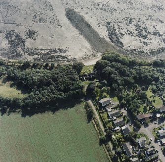 Oblique aerial view centred on the church and burial ground, with pier adjacent, taken from the NNE.