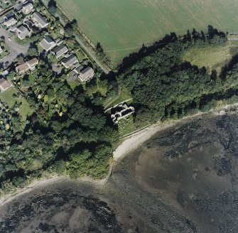 Oblique aerial view centred on the church and burial ground, with pier adjacent, taken from the SSW.