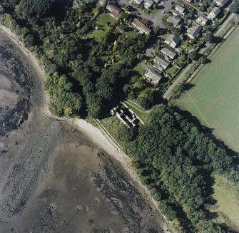 Oblique aerial view centred on the church and burial ground, with pier adjacent, taken from the SE.