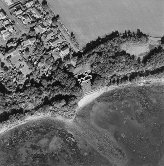 Oblique aerial view centred on the church and burial ground with pier adjacent, taken from the S.