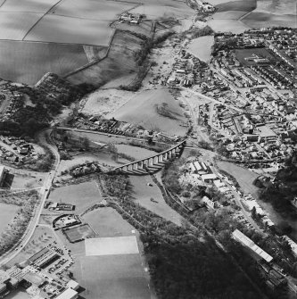 Oblique aerial view of Leslie centred on the village housing development designed by Wheeler and Sproson in 1952-56 with a railway viaduct adjacent, and recorded as part of the Wheeler and Sproson Project.  Taken from the ENE.