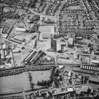 Oblique aerial view centred on the whisky distillery with the engineering works and works adjacent, taken from the SSE.