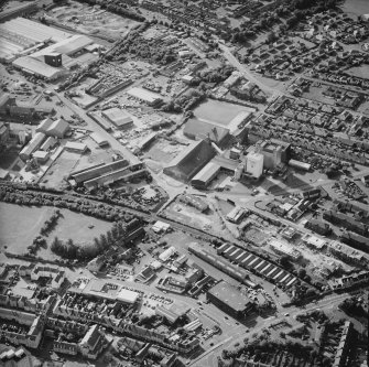 Oblique aerial view centred on the whisky distillery with the engineering works and works adjacent, taken from the SE.