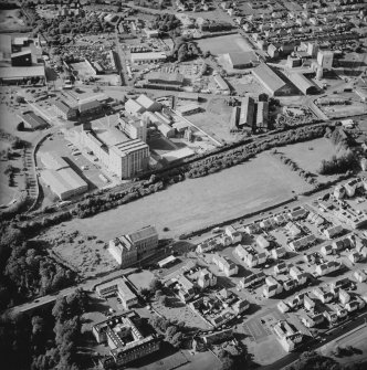 Oblique aerial view centred on the site of the works with the whisky distillery, engineering works, foundry and offices and works adjacent, taken from the SSE.