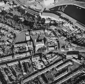 Oblique aerial view centred on the fire station with the works and college and the dock and harbour adjacent, taken from the WSW.