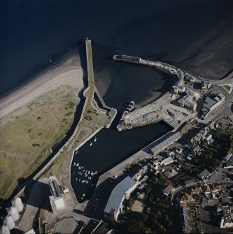 Oblique aerial view centred on the harbour and dock with the works and college adjacent, taken from the NNW.