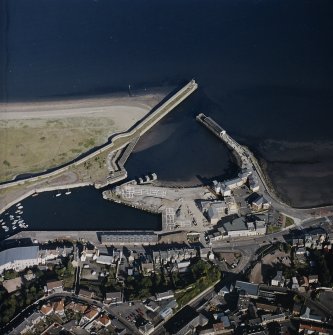 Oblique aerial view centred on the harbour and dock with the works and college adjacent, taken from the WNW.