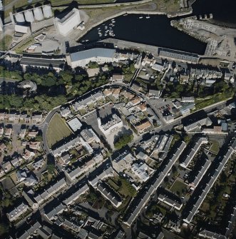 Oblique aerial view centred on the fire station with the works and college, the maltings and the dock and harbour adjacent, taken from the W.