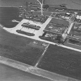 Oblique aerial view of Crail Airfield centred on the remains of the control tower, buildings, huts and aircraft hangars, taken from the ESE.