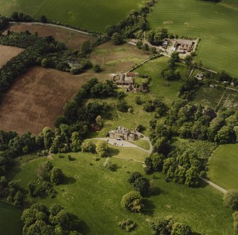 Oblique aerial view of Mountquhanie house, centred on the country house, 'dovecot', stables, farmsteading and the remains of a castle, taken from the SSE.