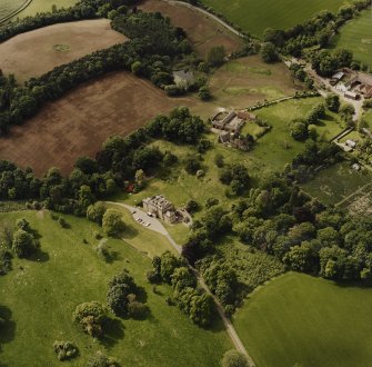 Oblique aerial view of Mountquhanie house, centred on the country house, 'dovecot', stables, farmsteading and the remains of a castle, taken from the SE.