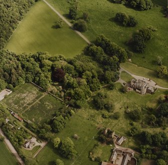 Oblique aerial view of Mountquhanie House centred on the country house, 'dovecot', stables and the remains of a castle, taken from the NW.