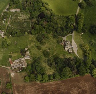Oblique aerial view of Mountquhanie House centred on the country house, 'dovecot', stables and the remains of a castle, taken from the WSW.