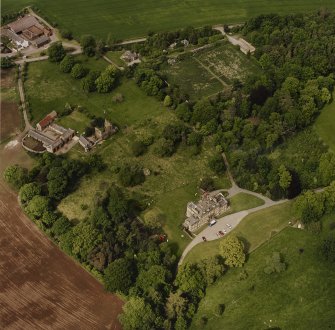 Oblique aerial view of Mountquhanie house, centred on the country house, 'dovecot', stables, farmsteading and the remains of a castle, taken from the SSW.
