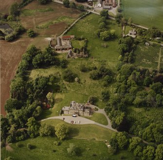 Oblique aerial view of Mountquhanie house, centred on the country house, 'dovecot', farmsteading, stables and the remains of a castle, taken from the SSE.