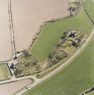 Oblique aerial view centred on the farmsteading, manse and walled garden, with the church, churchyard and war memorial adjacent, taken from the N.