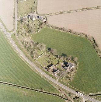 Oblique aerial view centred on the farmsteading, manse and walled garden, with the church, churchyard and war memorial adjacent, taken from the W.