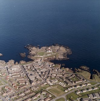 Oblique aerial view centred on the lighthouse with the school and churches adjacent, taken from the W.