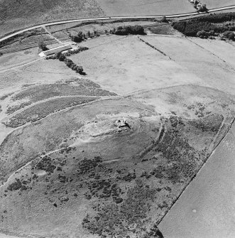 Oblique aerial view of Dunnideer centred on the remains of a fort and tower-house, taken from the NE.