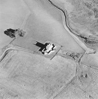 Oblique aerial view of Corgarff castle centred on the tower-house with the remains of a pond, quarry and the cropmarks of a building adjacent, taken from the WSW.