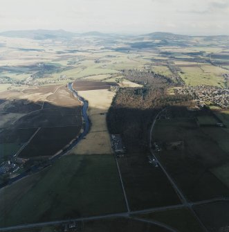 General oblique aerial view looking across the Howe of Alford down the River Don towards Bennachie and Cairn William with Montgarrie and Alford in the middle-distance, taken from the W.  The bottom half of the image is in shadow.