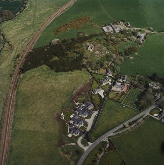 Oblique aerial view of the village centred on the burial-ground, manse and the remains of the church with the farmsteading adjacent, taken from the WSW.