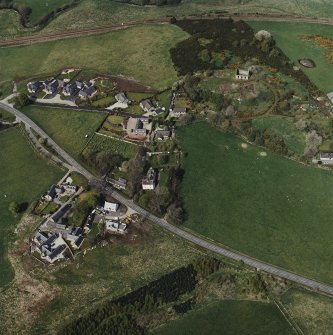 Oblique aerial view of the village centred on the burial-ground, manse and the remains of the church with the farmsteading adjacent, taken from the S.