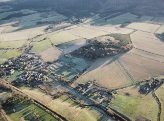 Oblique aerial view centred on the visitor centre, experimental archaeology site and the remains of the enclosure with the village adjacent, taken from the NW.