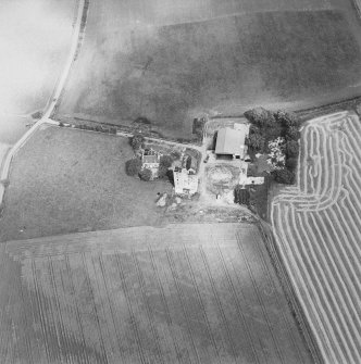 Oblique aerial view of Blervie Castle centred on the remains of a castle or tower-house with attached and adjacent farm buildings, taken from the SW.