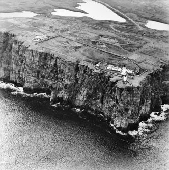 General oblique aerial view looking over the cliffs at Easter Head, Dunnet, to the lighthouse, radar station and the remains of the cairn, taken from the N.