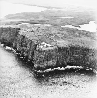 General oblique aerial view looking over the cliffs at Easter Head, Dunnet, to the lighthouse, radar station and the remains of the cairn, taken from the NW.