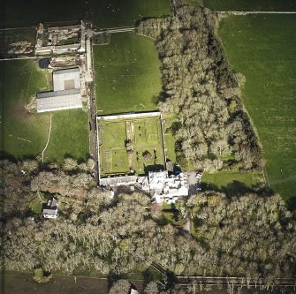 Oblique aerial view centred on the country house and walled garden with the farmsteading adjacent, taken from the W.