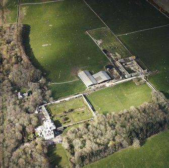 Oblique aerial view centred on the country house and walled garden with the farmsteading adjacent, taken from the SSW.