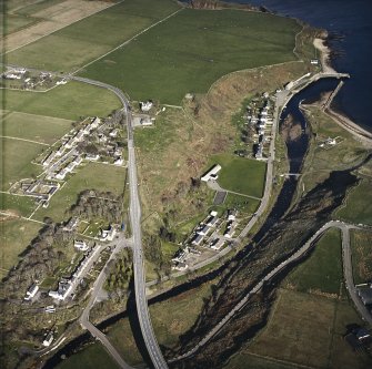 Oblique aerial view of Dunbeath centred on the hall, harbour, fishing station and footbridge with the road bridge adjacent, taken from the WNW.