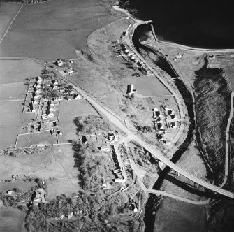 Oblique aerial view of Dunbeath centred on the hall, harbour, fishing station and footbridge with the road bridge adjacent, taken from the NW.