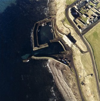 Oblique aerial view centred on the harbour, with the warehouse, pillbox and icehouse adjacent, taken from the W.