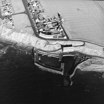 Oblique aerial view centred on the harbour with the warehouse and pillbox adjacent, taken from the SSW.